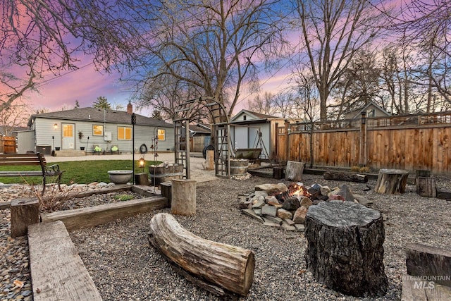 yard at dusk with entry steps, an outdoor structure, and fence private yard