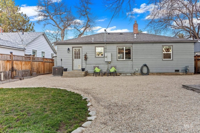 rear view of house with central AC, roof with shingles, a lawn, a chimney, and a fenced backyard