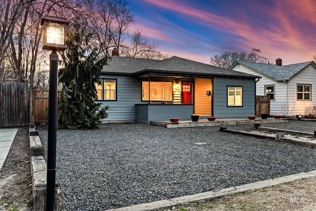 view of front of home with a shingled roof and fence