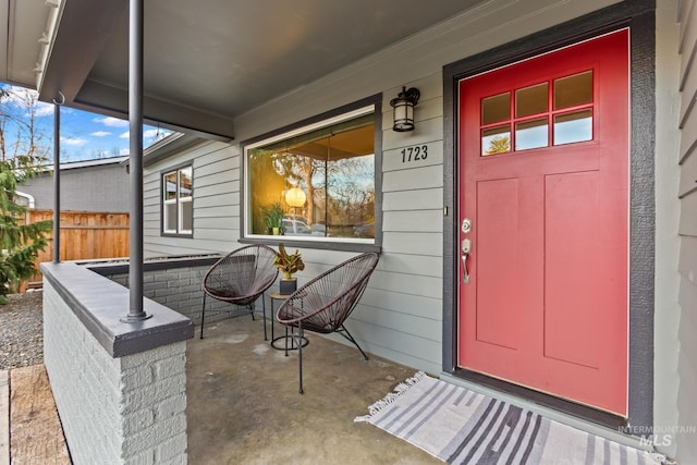 entrance to property with covered porch and fence