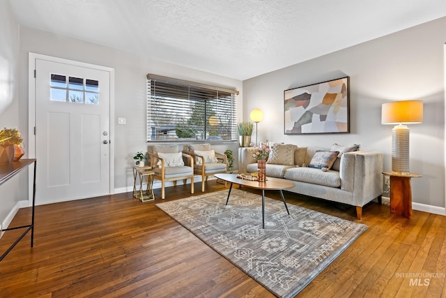 living room with baseboards, a textured ceiling, and hardwood / wood-style floors