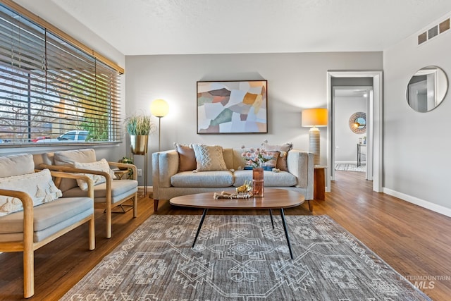 living area with visible vents, baseboards, and wood finished floors