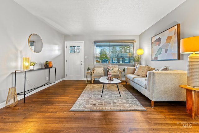 living room with baseboards, a textured ceiling, vaulted ceiling, and hardwood / wood-style flooring