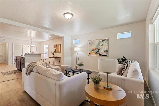 201 W Lava Fls, Meridian, ID 83646 - living room featuring light wood-type flooring, a chandelier, baseboards, and plenty of natural light