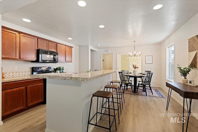 201 W Lava Fls, Meridian, ID 83646 - kitchen with black microwave, light wood-style floors, range with electric cooktop, a breakfast bar, and recessed lighting