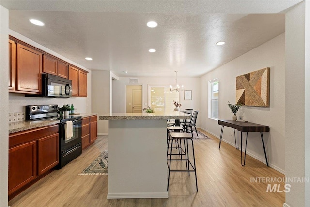 201 W Lava Fls, Meridian, ID 83646 - kitchen featuring black appliances, light wood finished floors, a breakfast bar, a chandelier, and a center island