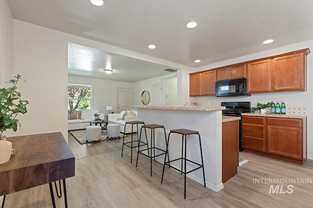 201 W Lava Fls, Meridian, ID 83646 - kitchen featuring black appliances, light wood-style flooring, brown cabinets, a kitchen bar, and open floor plan