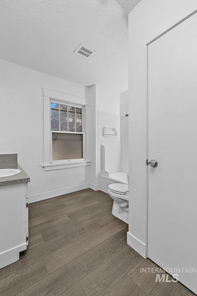135 Davis Ave, Nampa, ID 83651 - bathroom featuring vanity, toilet, a textured ceiling, wood finished floors, and baseboards