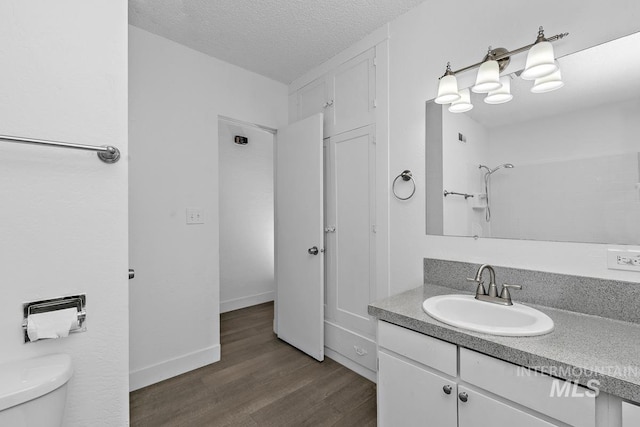 135 Davis Ave, Nampa, ID 83651 - bathroom with vanity, wood finished floors, toilet, a textured ceiling, and a shower