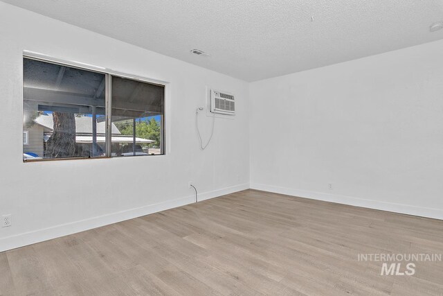135 Davis Ave, Nampa, ID 83651 - empty room with a wall unit AC, wood finished floors, baseboards, and a textured ceiling