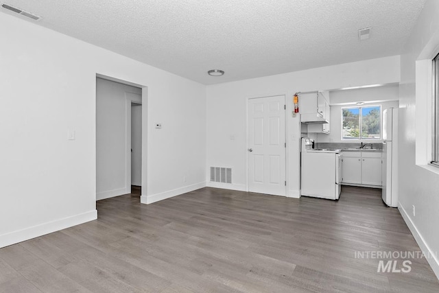 135 Davis Ave, Nampa, ID 83651 - unfurnished living room featuring a textured ceiling, dark wood finished floors, a sink, washer / clothes dryer, and baseboards