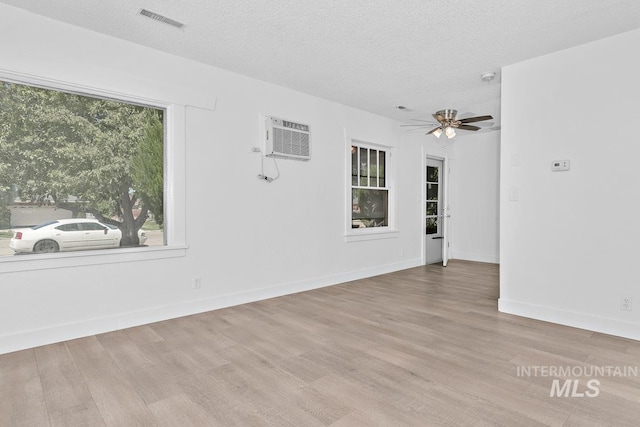 135 Davis Ave, Nampa, ID 83651 - empty room with an AC wall unit, wood finished floors, a ceiling fan, baseboards, and a textured ceiling