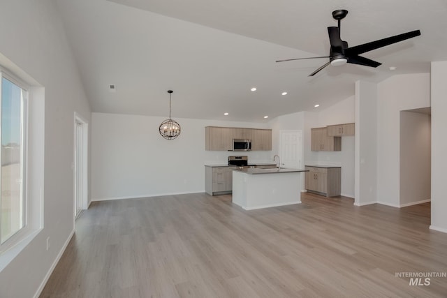 kitchen with pendant lighting, appliances with stainless steel finishes, sink, an island with sink, and lofted ceiling