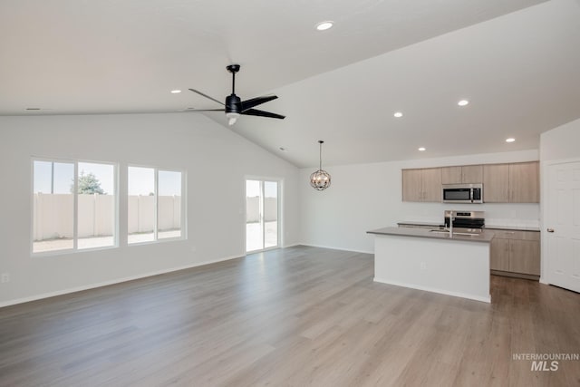 kitchen with ceiling fan with notable chandelier, lofted ceiling, stainless steel appliances, light hardwood / wood-style floors, and a kitchen island with sink