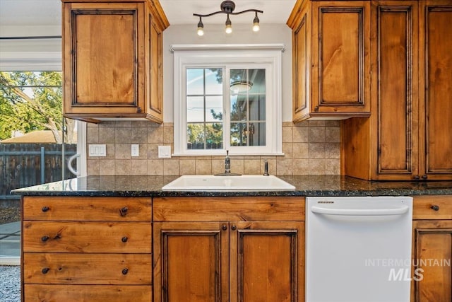 kitchen featuring sink, a healthy amount of sunlight, dishwasher, and dark stone countertops