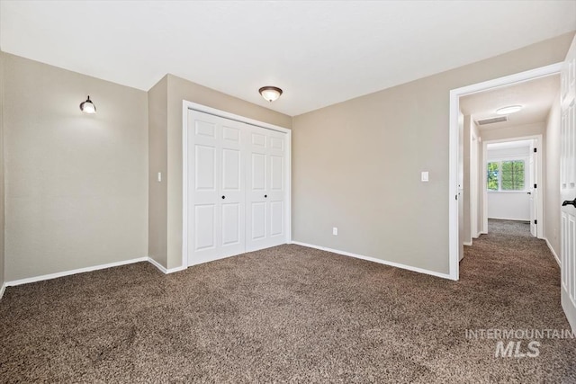 unfurnished bedroom featuring dark colored carpet and a closet