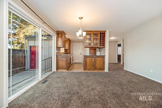 kitchen with sink, an inviting chandelier, decorative light fixtures, and light colored carpet