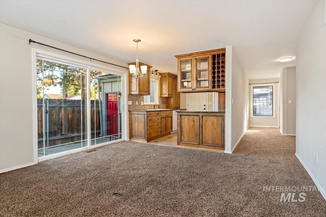 kitchen featuring sink, backsplash, hanging light fixtures, a chandelier, and light colored carpet