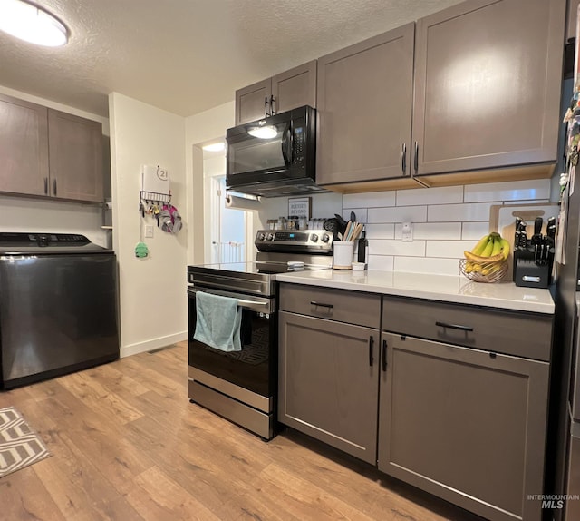 kitchen featuring washer / dryer, electric stove, light wood-style flooring, gray cabinets, and black microwave