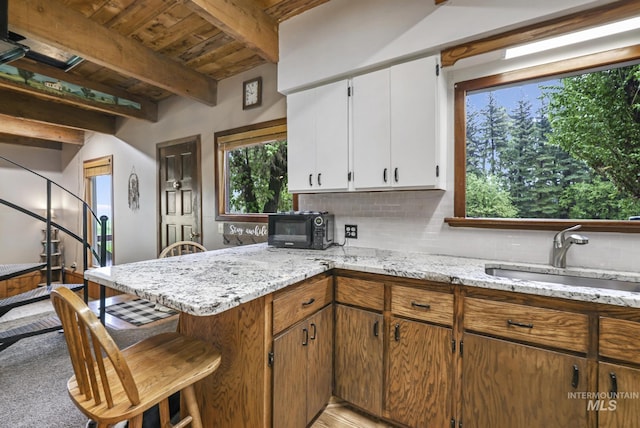 1011 E 1000 S, Albion, ID 83311 - kitchen with a sink, decorative backsplash, a peninsula, white cabinets, and a breakfast bar