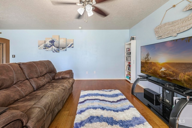 living room featuring wood-type flooring, a textured ceiling, and ceiling fan