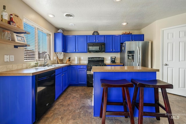 kitchen featuring a textured ceiling, black appliances, blue cabinets, and a breakfast bar