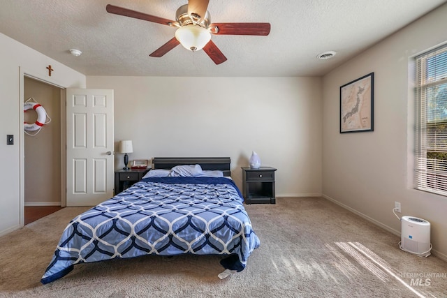 carpeted bedroom featuring ceiling fan and a textured ceiling