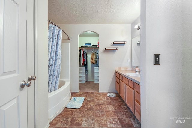 bathroom featuring shower / bath combo with shower curtain, a textured ceiling, and vanity