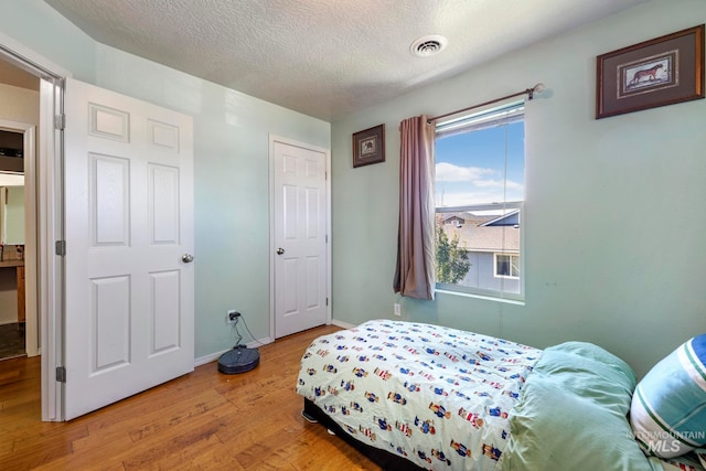 bedroom featuring light wood-type flooring and a textured ceiling