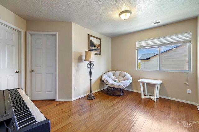 living area with a textured ceiling and hardwood / wood-style flooring