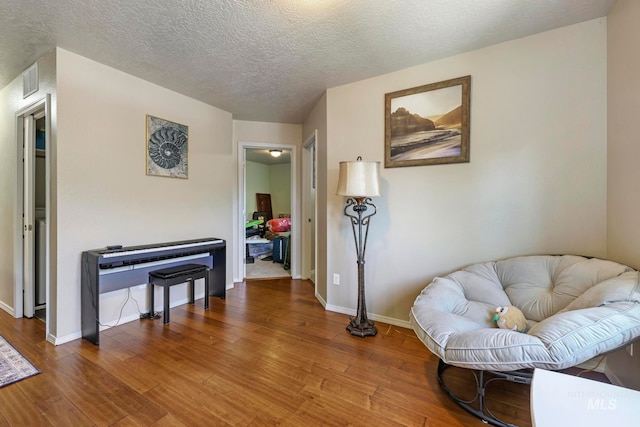 living area featuring a textured ceiling and hardwood / wood-style flooring