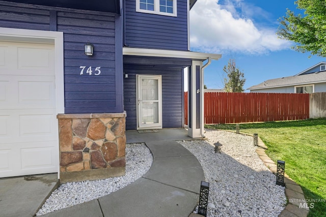 property entrance with a garage and a lawn