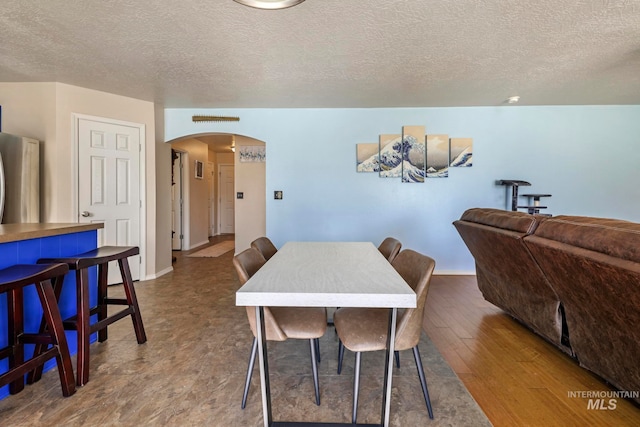 dining space featuring wood-type flooring and a textured ceiling