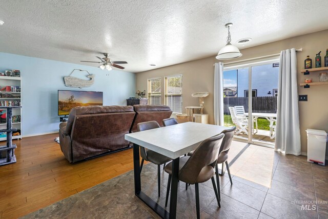 dining room with wood-type flooring, ceiling fan, and a textured ceiling