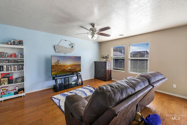 living room featuring wood-type flooring, a textured ceiling, and ceiling fan