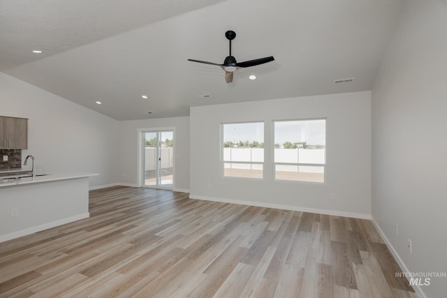 unfurnished living room with visible vents, light wood-style flooring, ceiling fan, and a sink