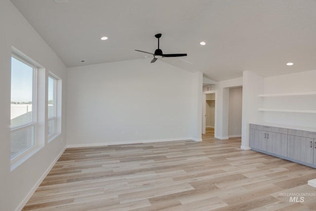 empty room with lofted ceiling, a ceiling fan, baseboards, and light wood finished floors