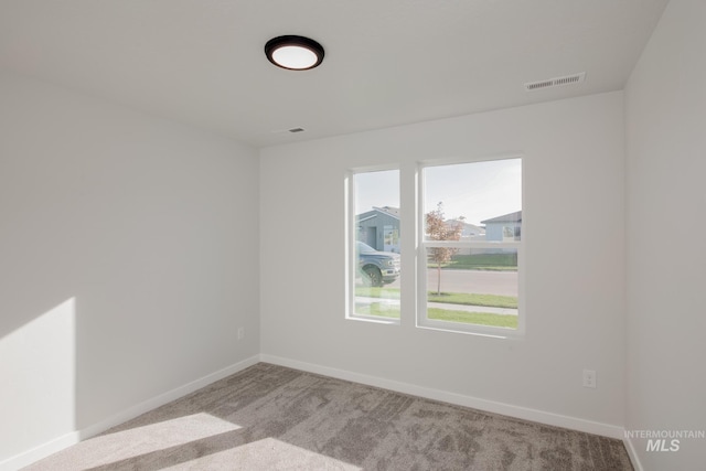 spare room with visible vents, baseboards, and carpet