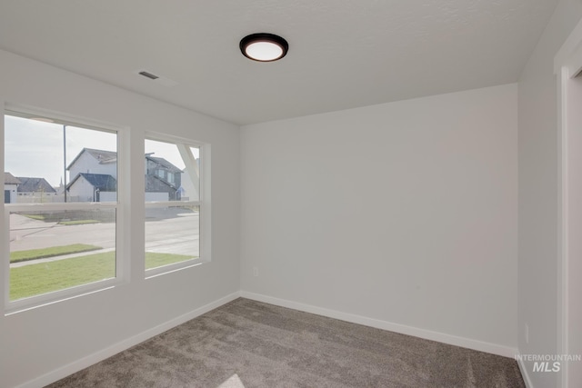 carpeted spare room with visible vents and baseboards