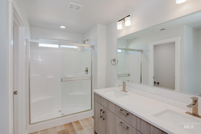 bathroom with wood finished floors, visible vents, a stall shower, and a sink