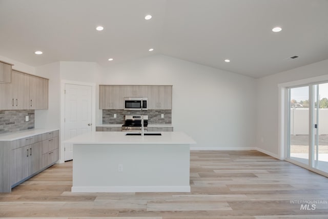 kitchen with stainless steel appliances, light countertops, lofted ceiling, and modern cabinets