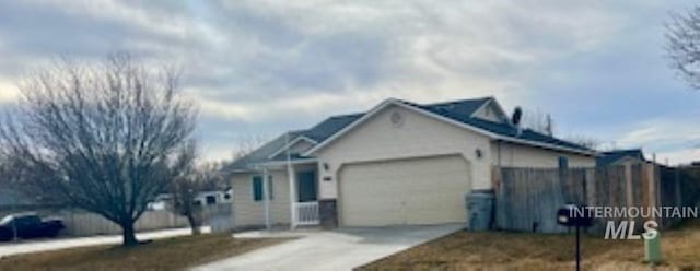 view of front of property featuring concrete driveway, an attached garage, and fence