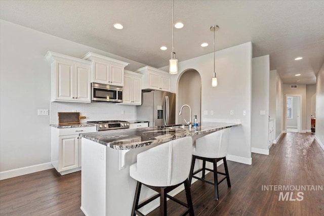 9753 W Wildbranch, Star, ID 83669 - kitchen with appliances with stainless steel finishes, dark wood-style flooring, a kitchen bar, dark stone countertops, and recessed lighting