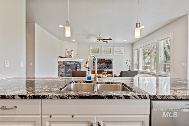 9753 W Wildbranch, Star, ID 83669 - kitchen with a fireplace, dishwashing machine, ceiling fan, dark stone countertops, and open floor plan