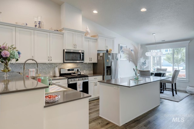 1987 S Defio Way, Meridian, ID 83642 - kitchen featuring appliances with stainless steel finishes, lofted ceiling, decorative backsplash, white cabinetry, and light wood-style flooring