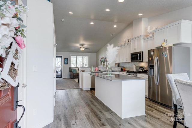 1987 S Defio Way, Meridian, ID 83642 - kitchen featuring stainless steel appliances, a peninsula, a ceiling fan, open floor plan, and light wood-style floors