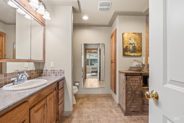 bathroom featuring vanity, toilet, and tasteful backsplash