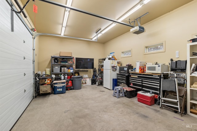 garage featuring white fridge and a garage door opener