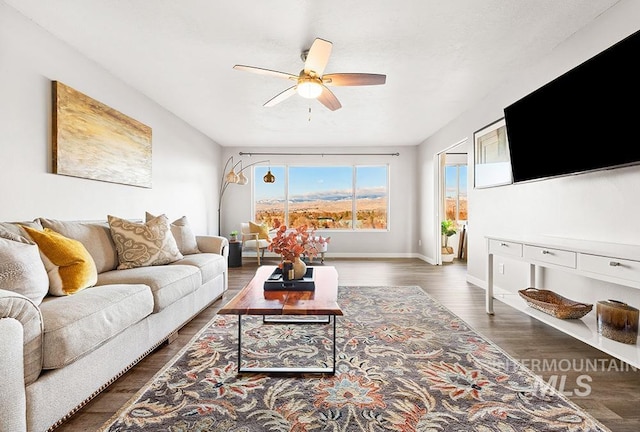 living room featuring dark wood-type flooring and ceiling fan