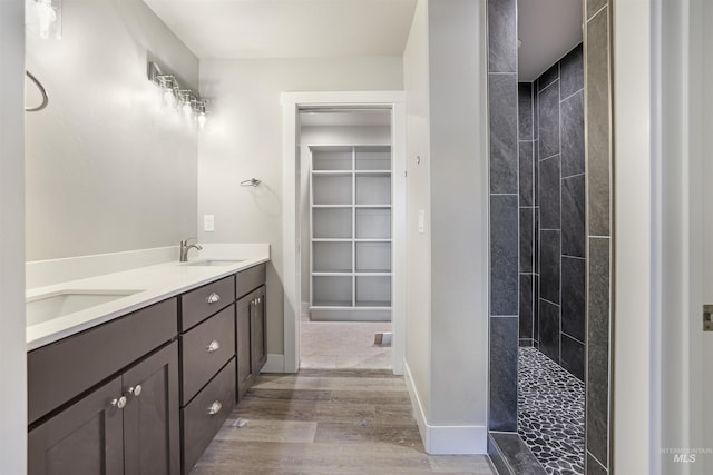 bathroom with wood-type flooring, vanity, and a tile shower